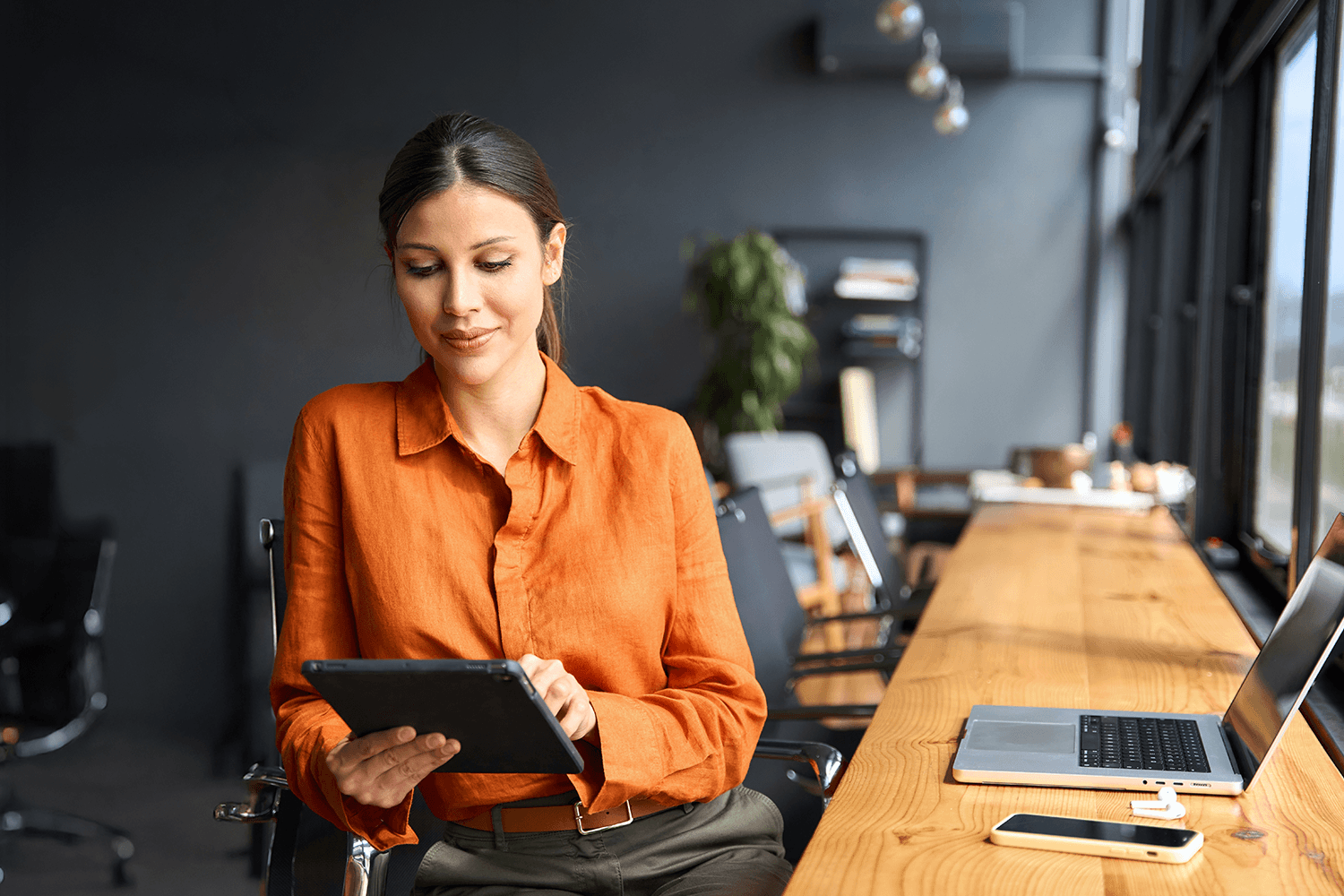 Professional woman using a tablet in a modern office workspace, symbolizing digital PR analysis and AI visibility tracking.