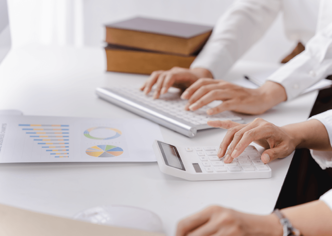 Professional reviewing financial reports while using a calculator and keyboard, illustrating digital PR budgeting, pricing models, and cost evaluation across campaign types and service tiers.