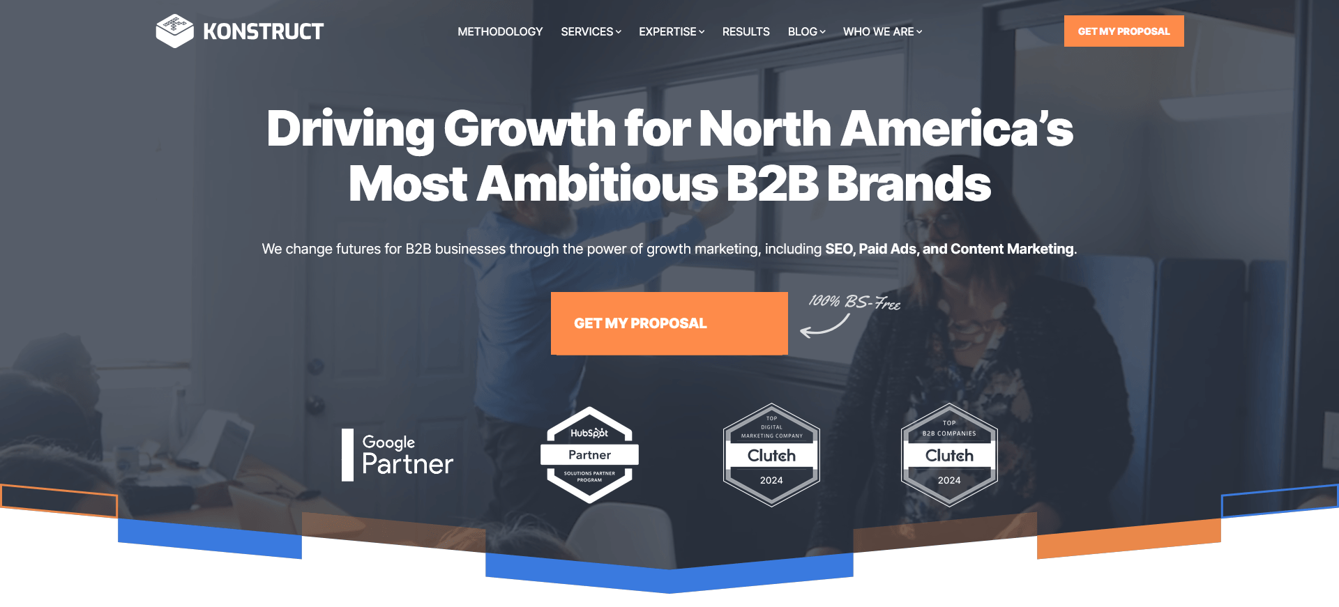 A bold headline on this homepage reads “Driving Growth for North America’s Most Ambitious B2B Brands,” with supporting text highlighting SEO, paid ads, and content marketing. Behind the text is a semi-transparent image of a business meeting, with award badges and an orange “Get My Proposal” button in the foreground.